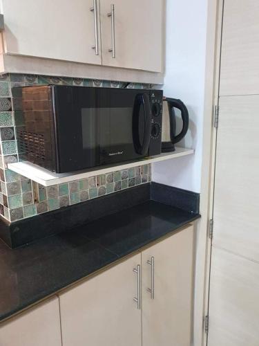 a black microwave on a shelf in a kitchen at Vangie's Place at SEA RESIDENCES in Manila