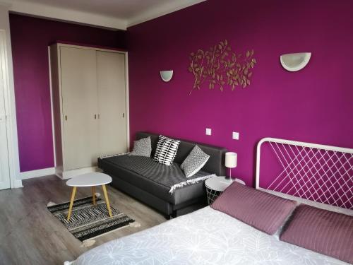 a purple bedroom with a bed and a couch at Hotel du Grand Monarque in Varennes-en-Argonne