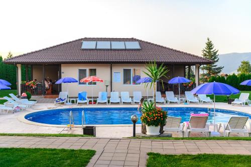 a house with a pool with chairs and umbrellas at Вилен комплекс Дарибел in Sapareva Banya