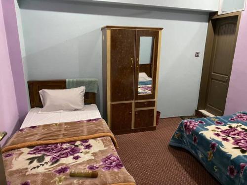 Habitación pequeña con 2 camas y armario en Golden Bite Hotel and Restaurant, en Alīābād