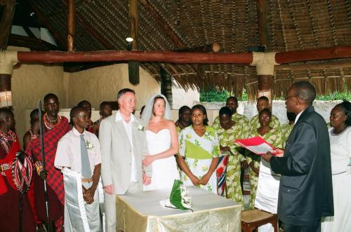 a bride and groom standing in front of a group of people at Pinewood Beach Resort and Spa in Diani Beach