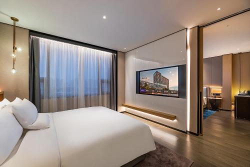 a bedroom with a white bed and a large window at Novotel Tianjin Drum Tower in Tianjin