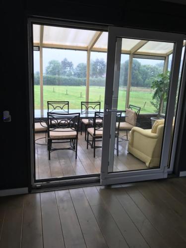a screened in porch with a table and chairs at Leuk vakantiewoning dijk woning met 3 slaapkamers dicht bij de Belgische grensen in Westdorpe