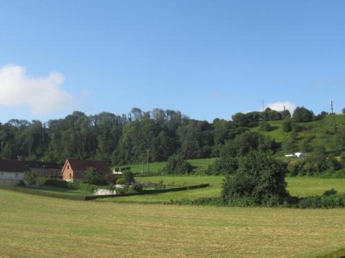 a field of grass with a house in the distance at La Belle symphonie in Vieil-Moutier
