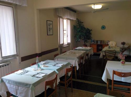 a dining room with four tables with white tablecloths at PENSIONE GARDENIA in Finale Ligure