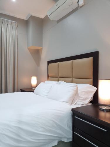 a bedroom with a large white bed with two lamps at Island Club by Smart City Stays in Cape Town