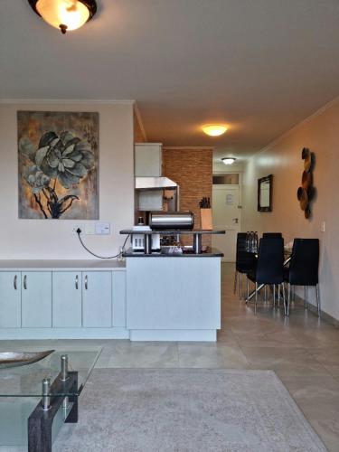 a kitchen with white cabinets and a table and chairs at Island Club by Smart City Stays in Cape Town