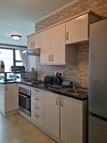 a kitchen with white cabinets and a stainless steel refrigerator at Island Club by Smart City Stays in Cape Town