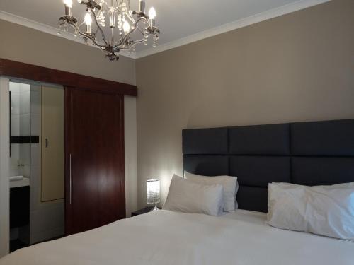 a bedroom with a large bed with a black headboard at Island Club by Smart City Stays in Cape Town