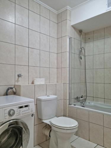 a bathroom with a toilet and a washing machine at Island Club by Smart City Stays in Cape Town