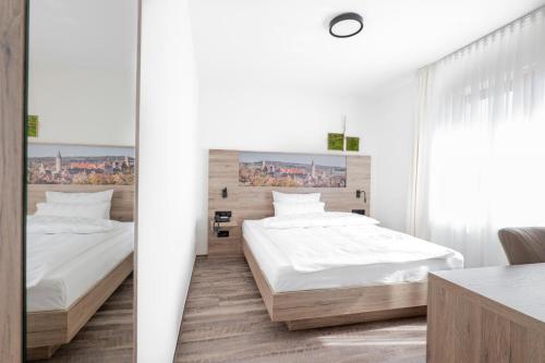 2 Betten in einem Zimmer mit weißen Wänden und einem Schreibtisch in der Unterkunft Landhotel Kirchberg in Kirchberg an der Jagst