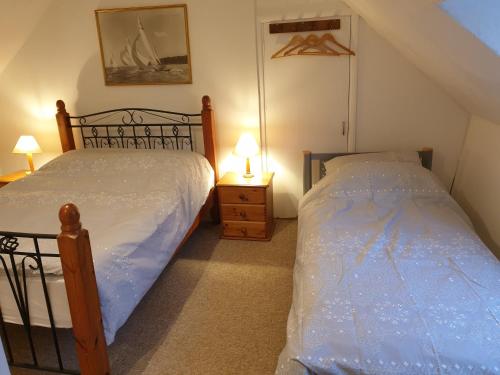 1 dormitorio con 2 camas individuales y 2 lámparas en The horse and panniers guest house. en North Luffenham