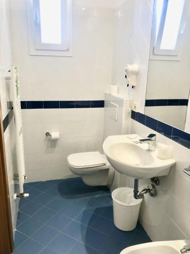 a white bathroom with a sink and a toilet at Hotel Boom in Rimini
