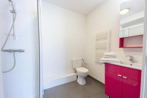 a bathroom with a toilet and a shower with red cabinets at Le Campus Appartement in Nice