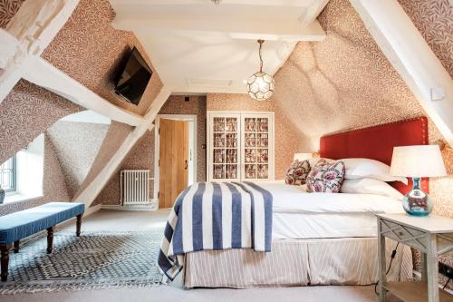 um quarto com uma cama grande num sótão em The Bay Tree Hotel em Burford