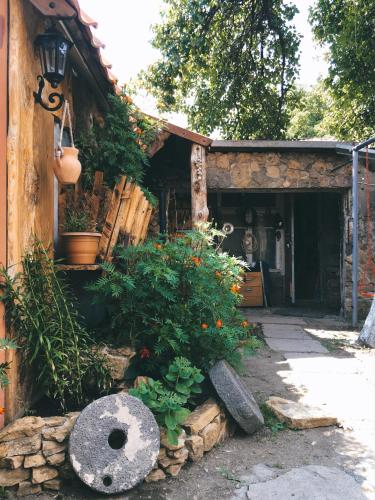 a person sitting in the doorway of a building with flowers at Alashkert Guesthouse ,Ալաշկերտ Հյուրատուն in Gyumri