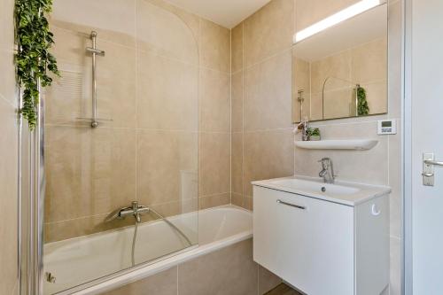 een badkamer met een bad, een wastafel en een douche bij Flat Marie in De Panne