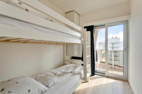 a bedroom with two bunk beds and a large window at Flat Marie in De Panne