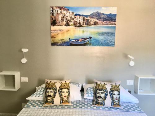 a bedroom with a bed with a painting on the wall at Amori di Sicilia in Cefalù