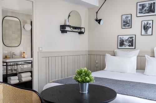 a hotel room with a bed and a table with a flower on it at Hôtel Hélios Opéra in Paris