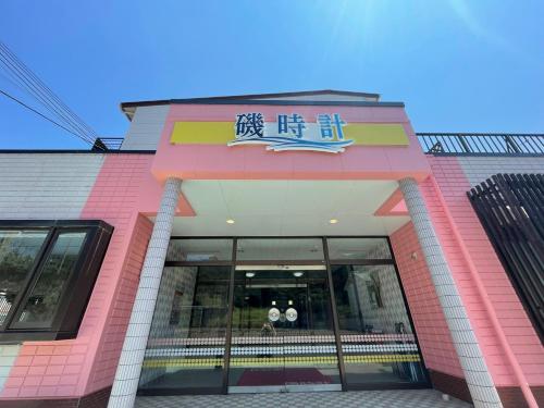 a pink building with a sign on the front of it at Hotel Isodokei in Shirahama