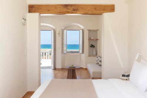 a bedroom with a bed and a view of the ocean at Ammothines Cycladic Suites in Naxos Chora