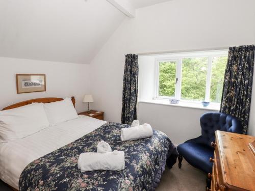 een slaapkamer met een bed en een blauwe stoel bij Silverthwaite Cottage in Ambleside