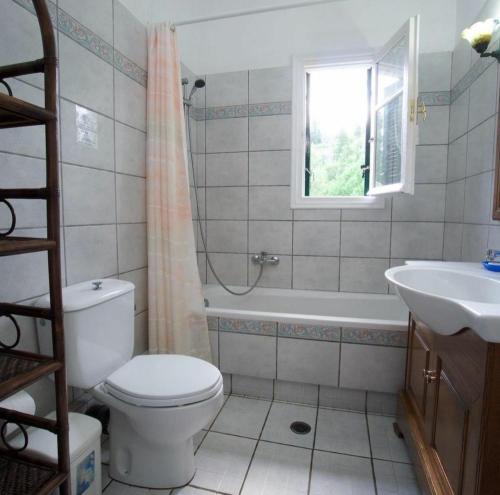 a bathroom with a toilet and a tub and a sink at Panorama Apartments Fiscardo in Fiskardho