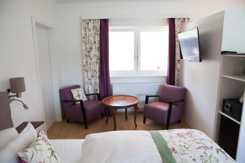 a hotel room with a bed and a table and chairs at Gasthof zum Goldenen Anker in Hainburg an der Donau