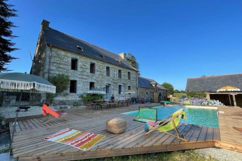 een terras met een zwembad en een huis bij La Lande du Rest - Le Quillio Magnifique ancienne ferme de notables avec piscine chauffée in Le Quillio