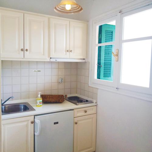 a kitchen with white cabinets and a sink and a window at Panorama Apartments Fiscardo in Fiskardho