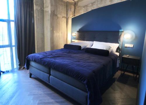 a bedroom with a large bed with a blue blanket at Bed, Bites & Business Hotel Rotterdam in Rotterdam