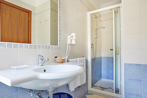 a bathroom with a white sink and a shower at Hotel Miramare in Caorle