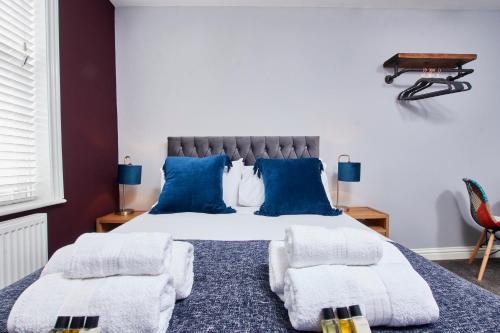 1 dormitorio con 1 cama grande con almohadas azules en Delven House, Apartment 5 en Castle Donington