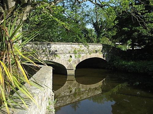 a stone bridge over a river in a park at Flynns of Termonfeckin Boutique Hotel in Termonfeckin