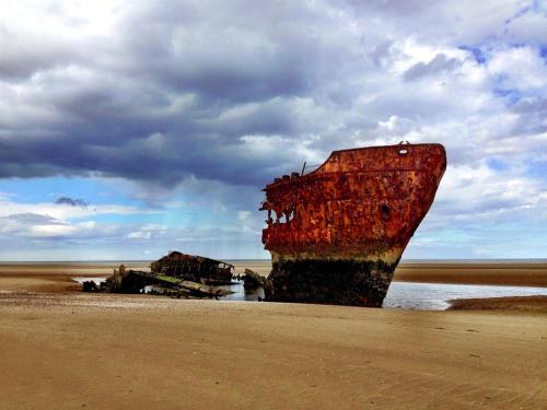 an old boat sitting on the shore of a beach at Flynns of Termonfeckin Boutique Hotel in Termonfeckin