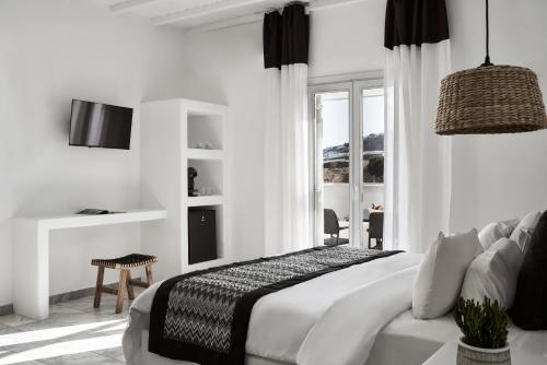 a white bedroom with a bed and a window at Mr & Mrs White Mykonos in Platis Yialos Mykonos