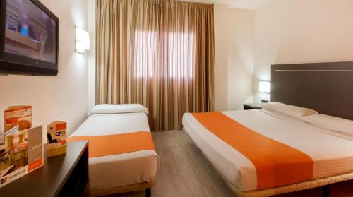 a hotel room with two beds and a flat screen tv at H2 Fuenlabrada in Fuenlabrada