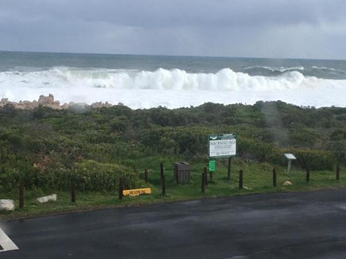 a road with a large wave in the ocean at Bungalow by the sea near Cape Town in Kleinmond