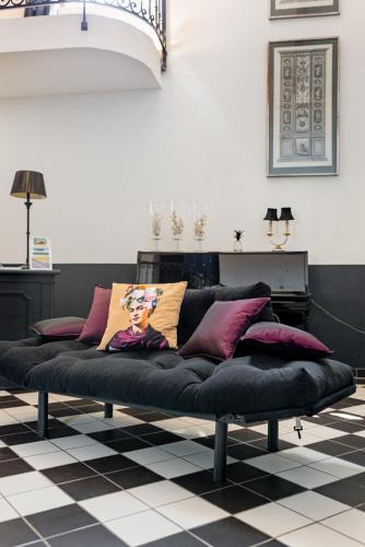 a black couch with pillows on a checkered floor at La Petite Aiguebonne in Allex