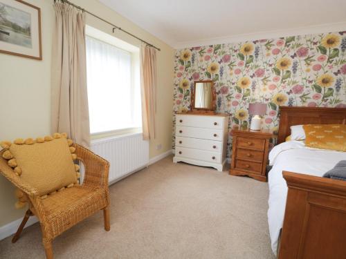 a bedroom with a bed and a chair and a window at 3 Springfort Cottages in Penrith