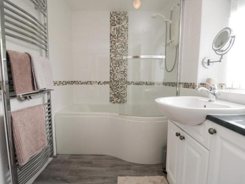 a white bathroom with a sink and a tub and a toilet at 3 Springfort Cottages in Penrith