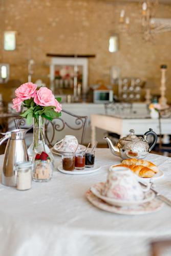 a table with a vase of roses and plates of food at La Petite Aiguebonne in Allex