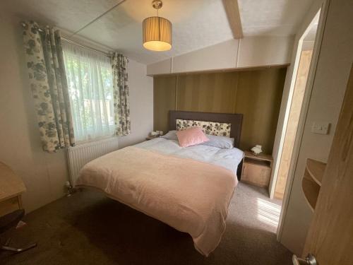 a bedroom with a bed with a pink pillow on it at Two Bedroom Caravan at Lilliarsedge in Jedburgh