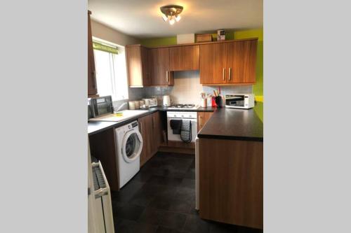 a kitchen with wooden cabinets and a washer and dryer at Dudley House **Staycation & Contractors** Sleeps 7 in Tipton