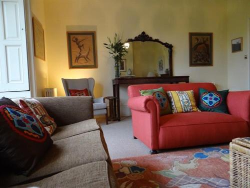 a living room with a couch and a red chair at Heyford House in Bicester