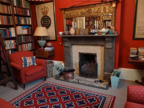 a living room with a fireplace and a red wall at Heyford House in Bicester