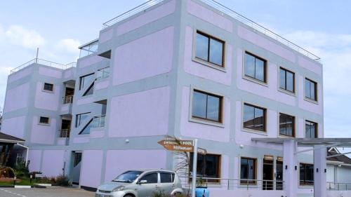 a white building with a car parked in front of it at Esiankiki Resort & Spa - Nanyuki in Nanyuki