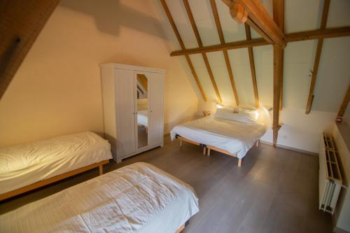 a attic bedroom with two beds and a cabinet at De Grote Linde in Oostkamp