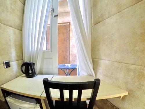 un tavolo e una sedia in una stanza con finestra di Blue Suite Vatican Guesthouse a Roma